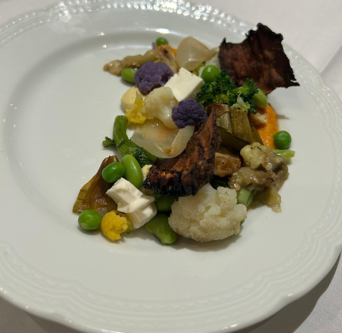 Piatto di verdure miste con cavolfiore viola, broccoli, piselli e tofu su crema di carote