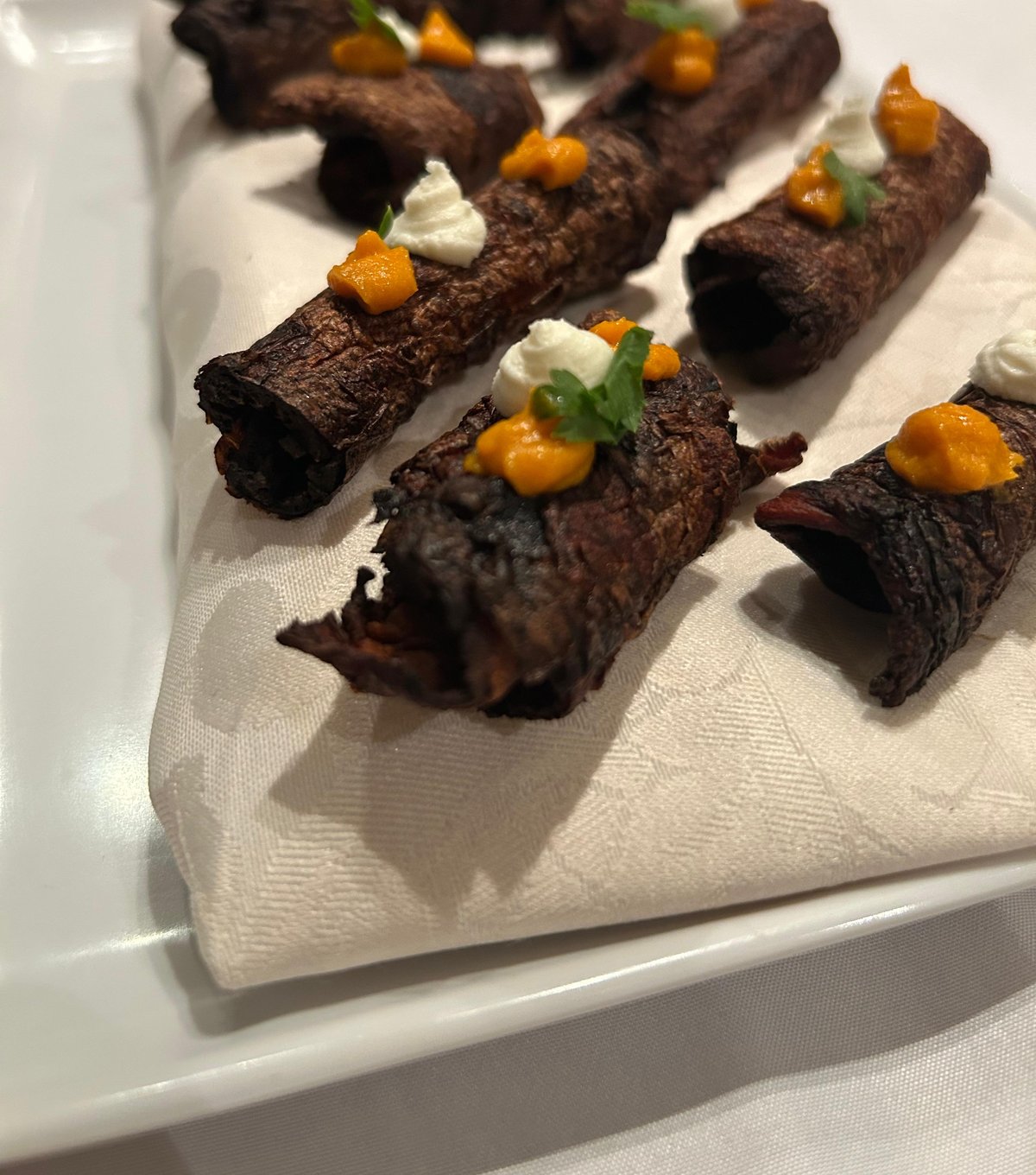 Involtini di verdura brasata con crema bianca e purea di carota, guarniti con erbe fresche