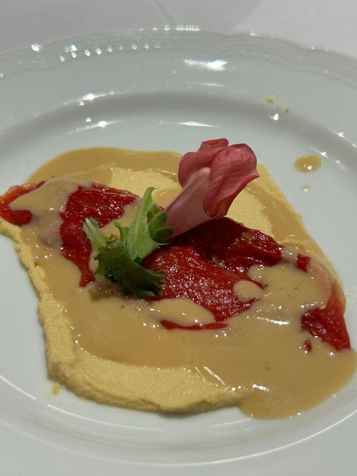 Crema gialla con peperone rosso arrosto, guarnita con fiore edule
