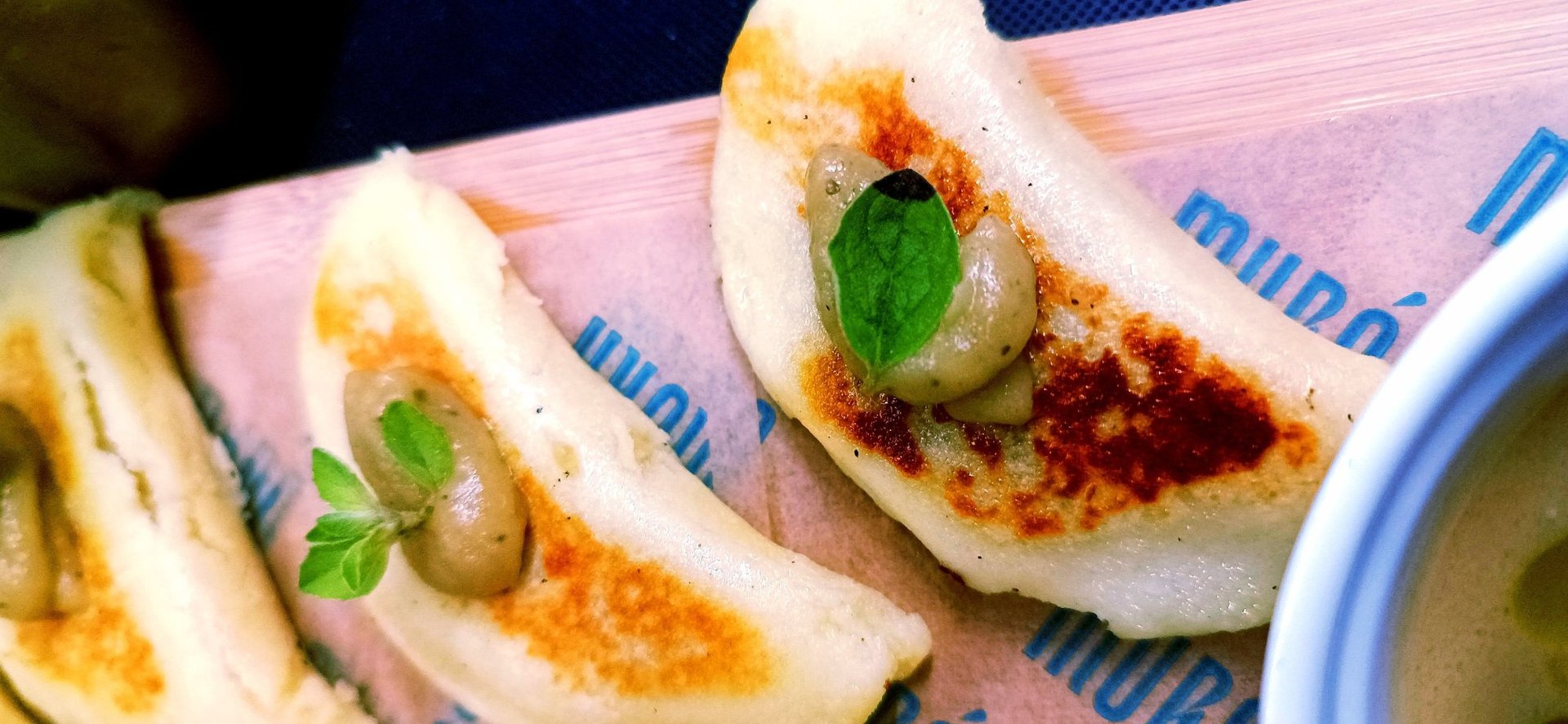 Primo piano di fagottini ripieni dorati in padella con foglie di basilico